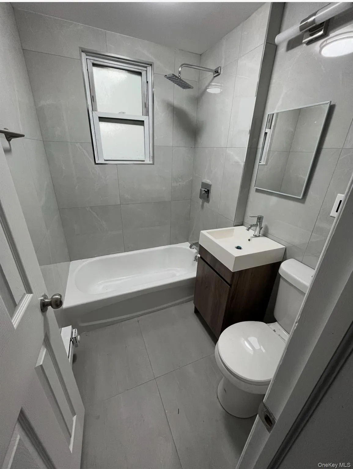 Bathroom featuring vanity, bathtub / shower combination, and tile walls Bathroom featuring vanity, bathtub / shower combination, and tile walls
