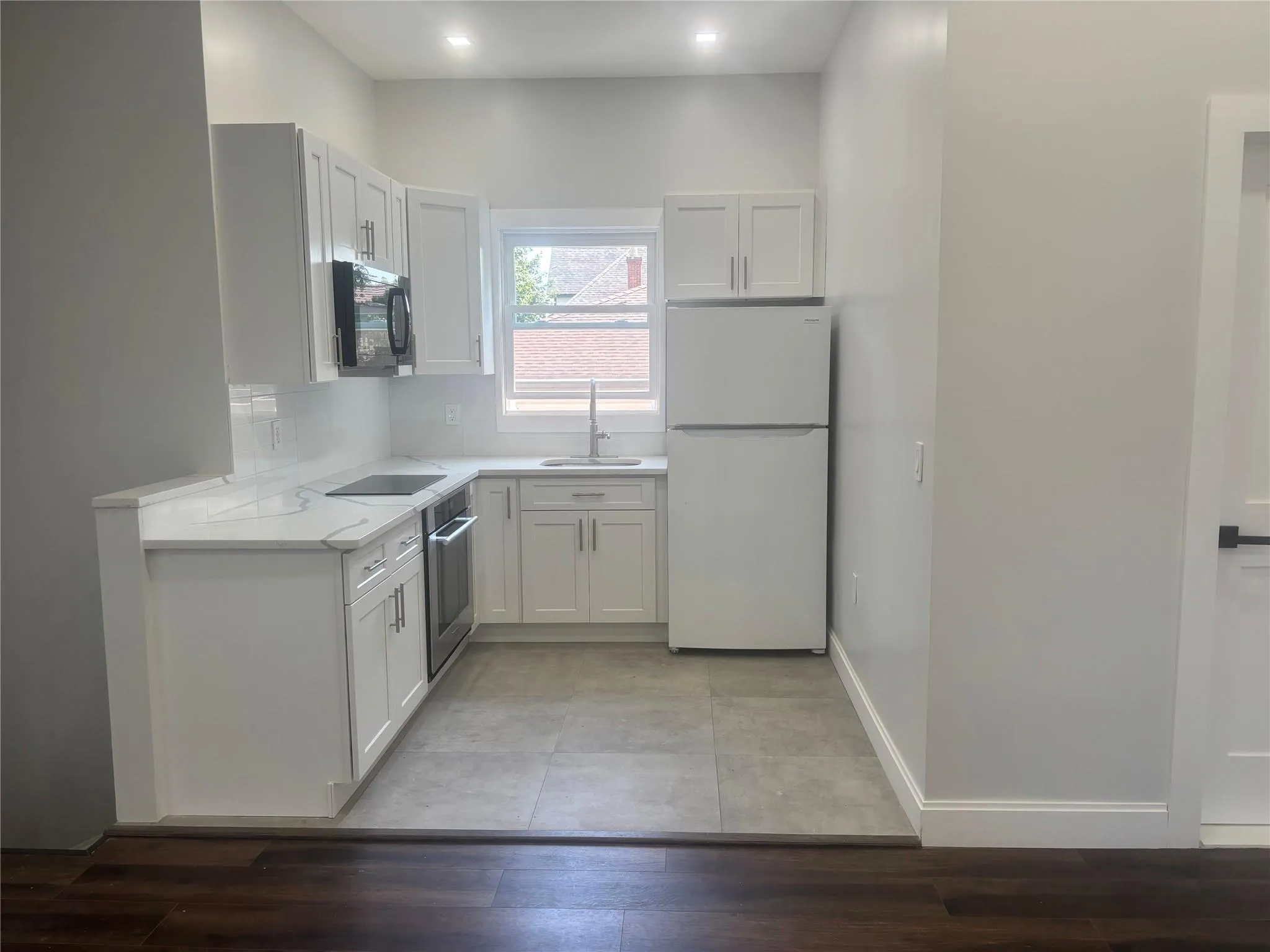 Kitchen featuring freestanding refrigerator, oven, white cabinetry, light wood finished floors, and recessed lighting Kitchen featuring freestanding refrigerator, oven, white cabinetry, light wood finished floors, and recessed lighting