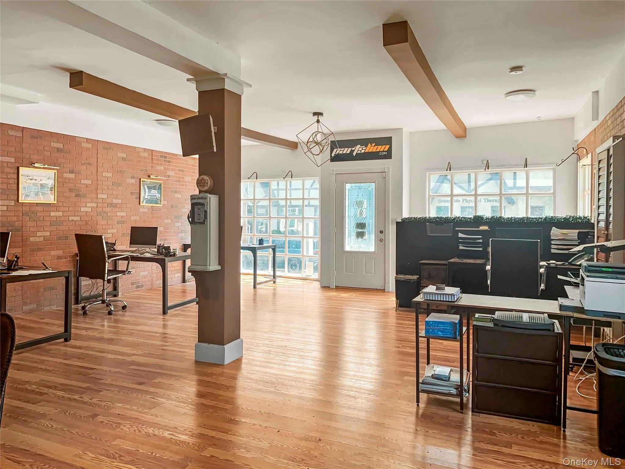 Office area featuring brick wall, wood finished floors, and beamed ceiling Office area featuring brick wall, wood finished floors, and beamed ceiling