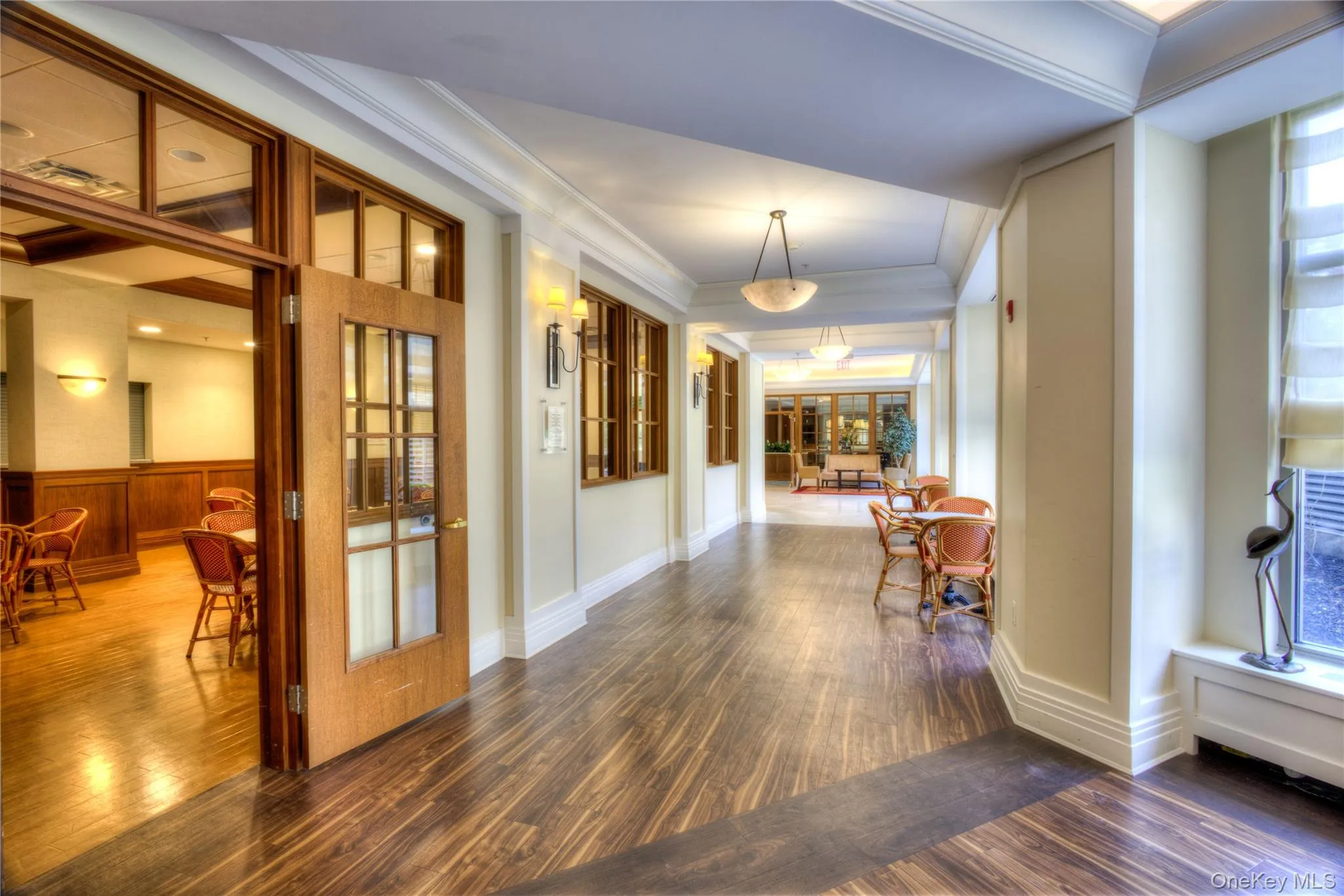 Corridor featuring wood finished floors, crown molding, and healthy amount of natural light Corridor featuring wood finished floors, crown molding, and healthy amount of natural light