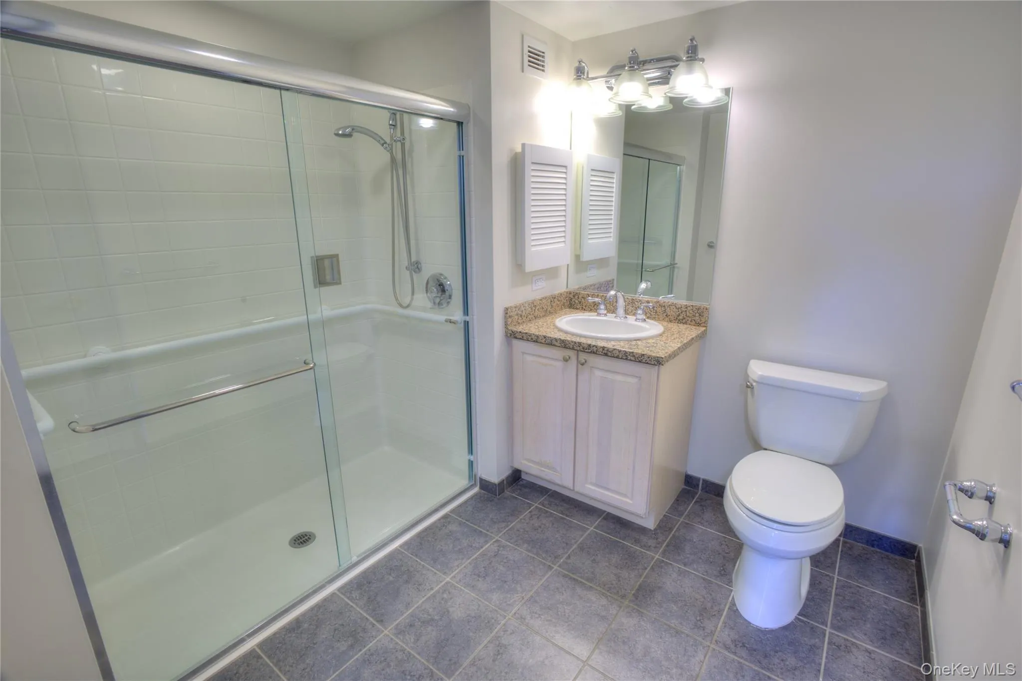 Bathroom with a shower stall, vanity, and tile patterned floors Bathroom with a shower stall, vanity, and tile patterned floors