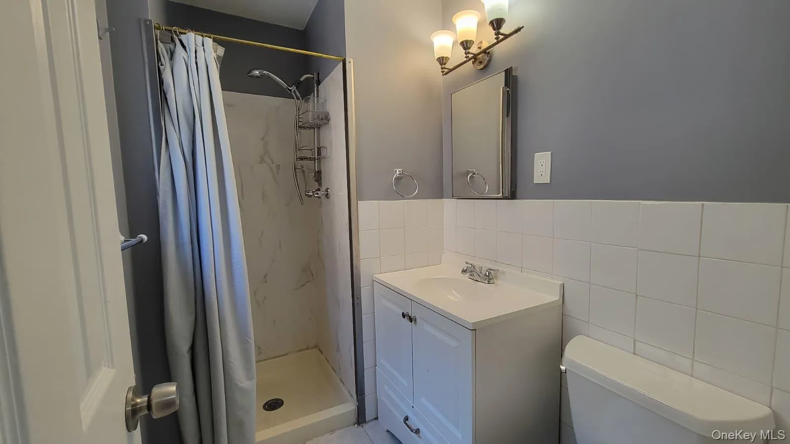 Full bathroom featuring vanity, a stall shower, and tile walls Full bathroom featuring vanity, a stall shower, and tile walls