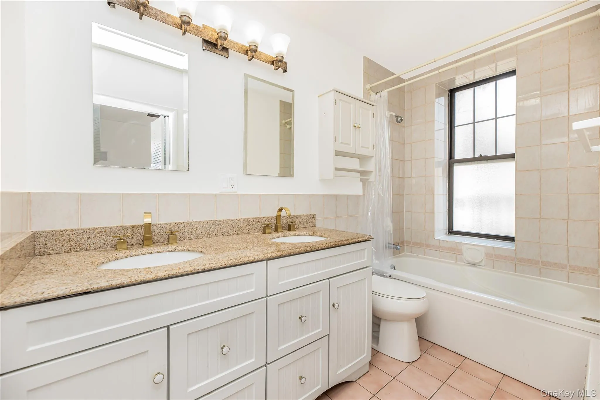 Full bathroom with tile patterned floors, double vanity, tub / shower combination, and tile walls Full bathroom with tile patterned floors, double vanity, tub / shower combination, and tile walls