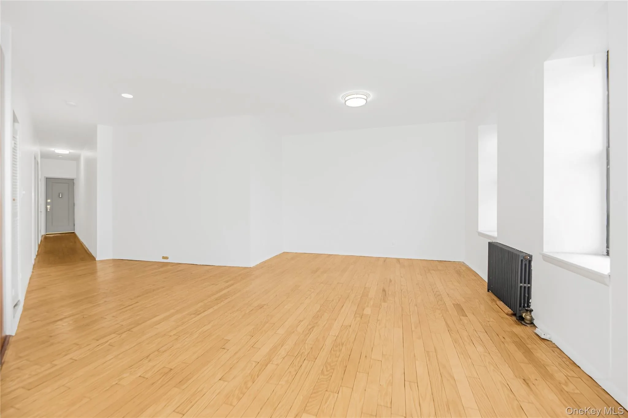 Empty room with light wood-type flooring, radiator, and recessed lighting Empty room with light wood-type flooring, radiator, and recessed lighting