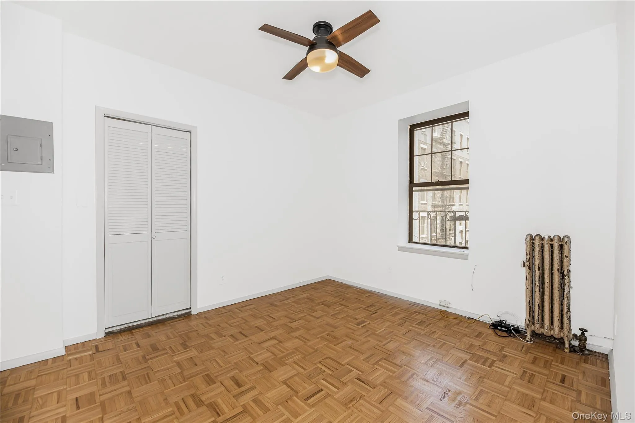 Empty room featuring radiator, electric panel, and a ceiling fan Empty room featuring radiator, electric panel, and a ceiling fan