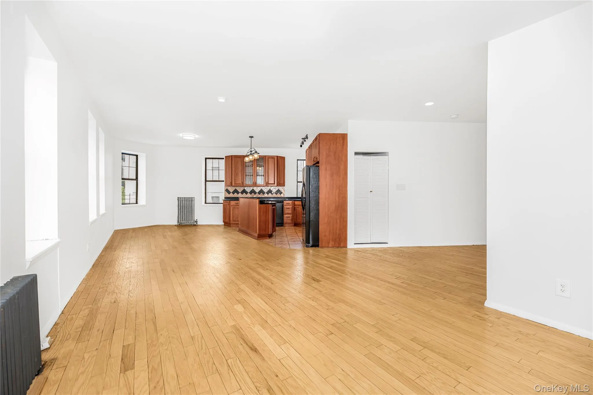 Unfurnished living room with light wood finished floors, radiator heating unit, and recessed lighting Unfurnished living room with light wood finished floors, radiator heating unit, and recessed lighting