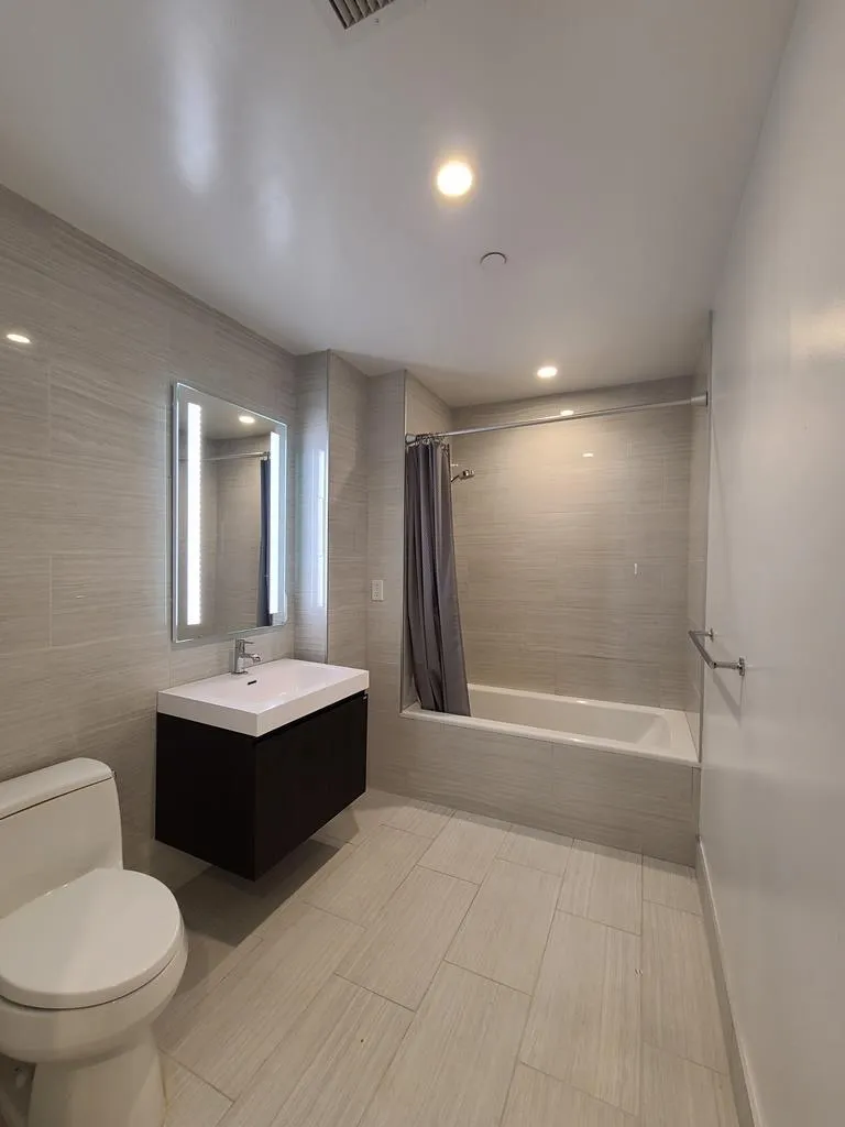 Full bath featuring tiled shower / bath, vanity, tile walls, and recessed lighting Full bath featuring tiled shower / bath, vanity, tile walls, and recessed lighting