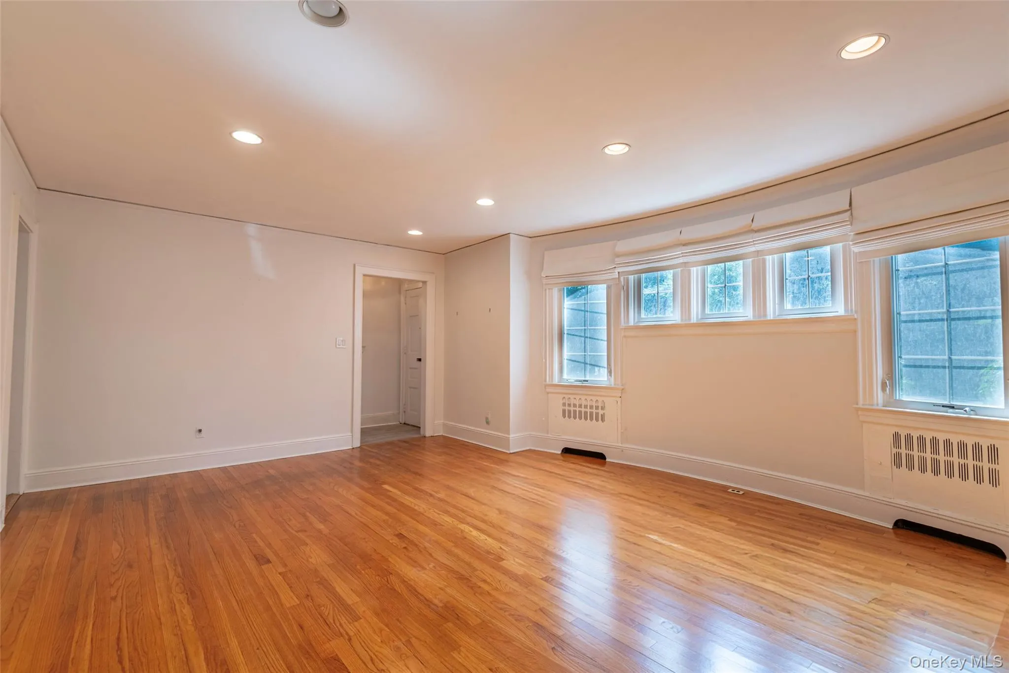 Empty room featuring recessed lighting, light wood-type flooring, and radiator heating unit Empty room featuring recessed lighting, light wood-type flooring, and radiator heating unit