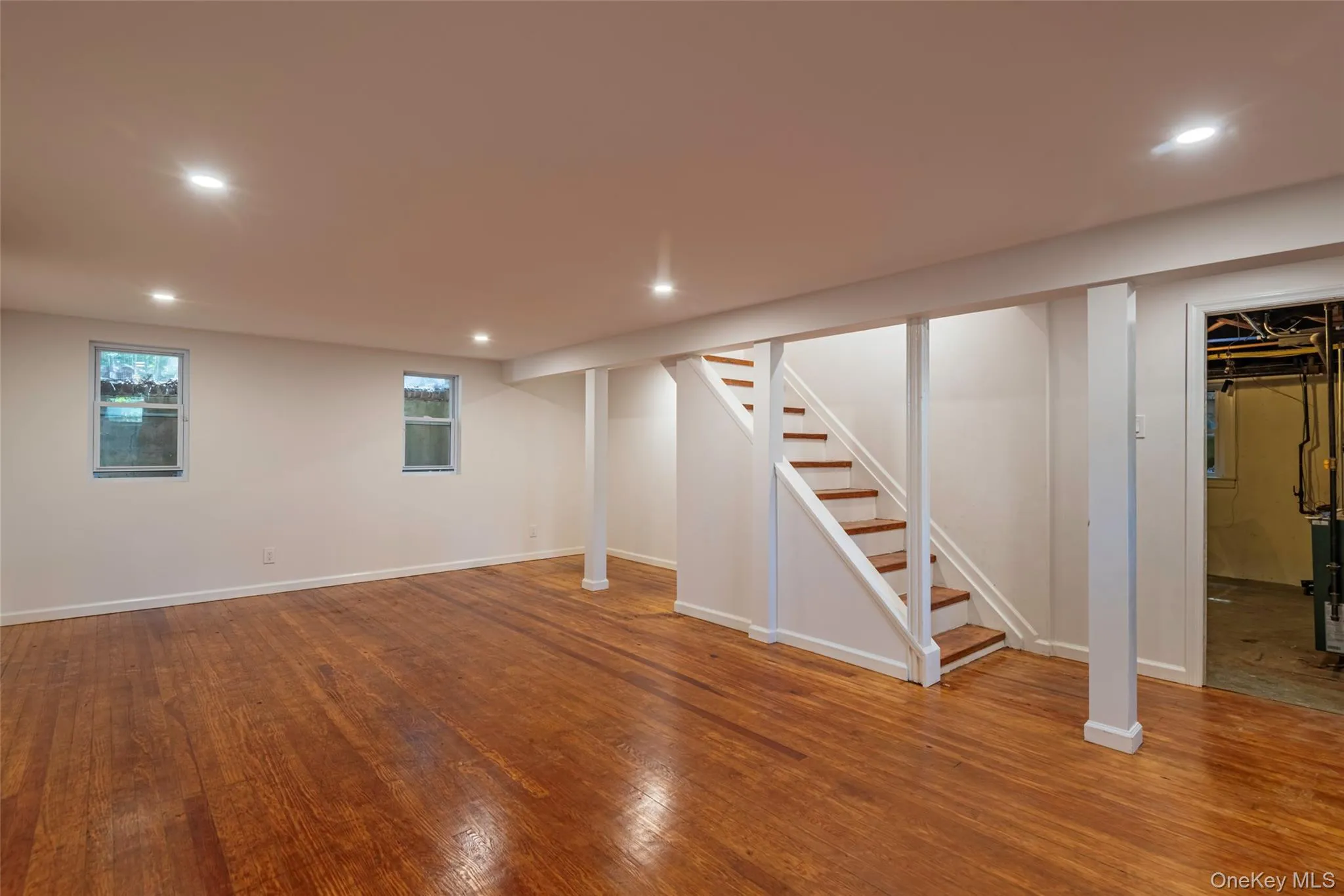 Basement with recessed lighting, stairway, wood-type flooring, and a heating unit Basement with recessed lighting, stairway, wood-type flooring, and a heating unit