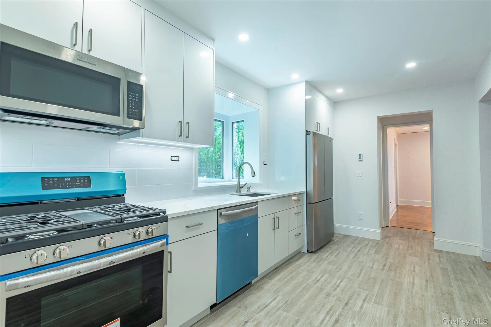 Kitchen with appliances with stainless steel finishes, white cabinets, tasteful backsplash, recessed lighting, and light wood-style flooring Kitchen with appliances with stainless steel finishes, white cabinets, tasteful backsplash, recessed lighting, and light wood-style flooring