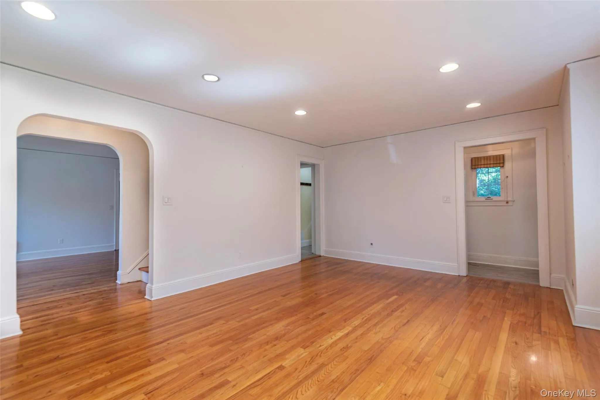 Unfurnished room featuring recessed lighting, light wood-style floors, and arched walkways Unfurnished room featuring recessed lighting, light wood-style floors, and arched walkways
