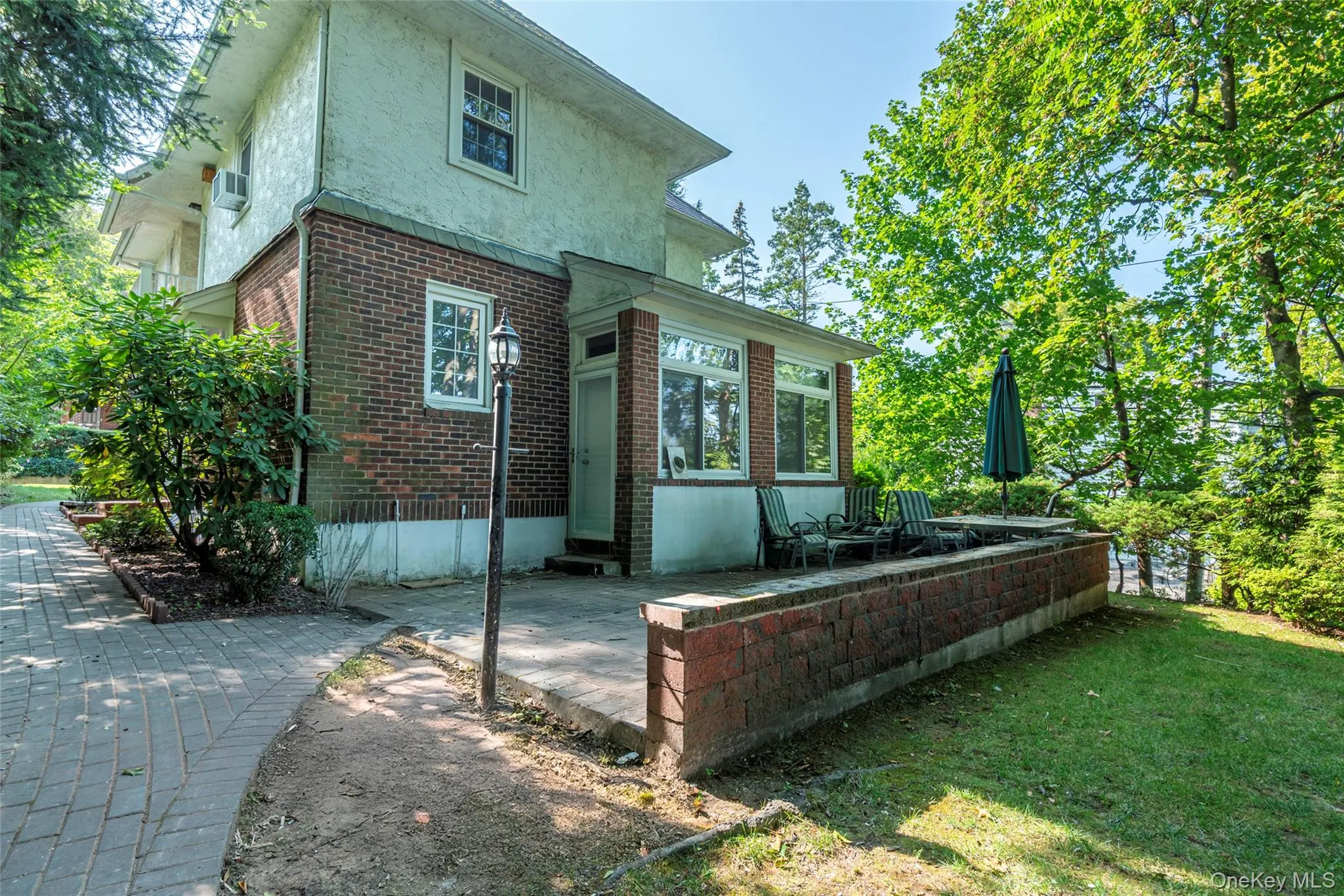 Rear view of house with brick siding, a patio, stucco siding, and a lawn Rear view of house with brick siding, a patio, stucco siding, and a lawn