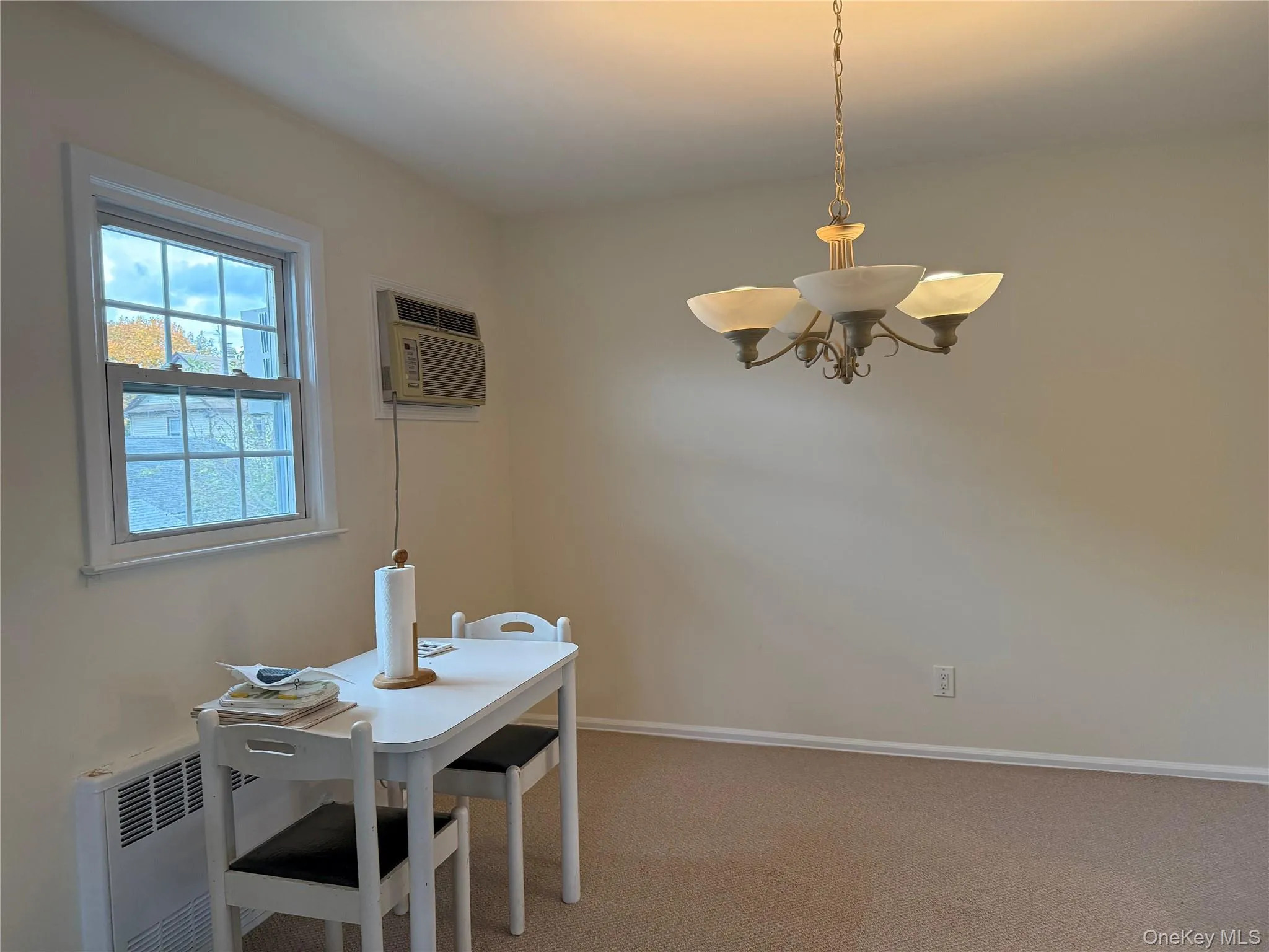 Dining room featuring carpet, an AC wall unit, and a chandelier Dining room featuring carpet, an AC wall unit, and a chandelier