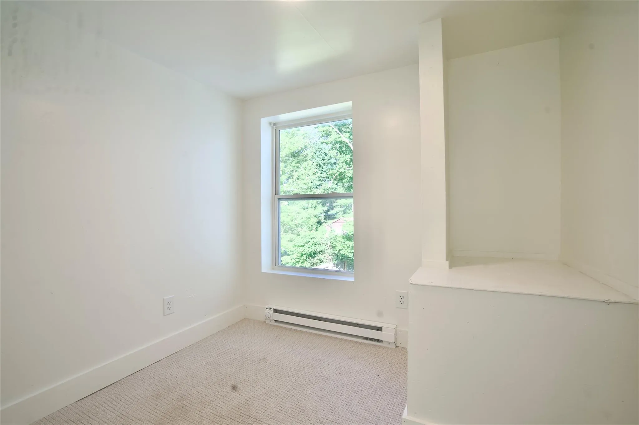 Carpeted empty room featuring a baseboard radiator and baseboards Carpeted empty room featuring a baseboard radiator and baseboards