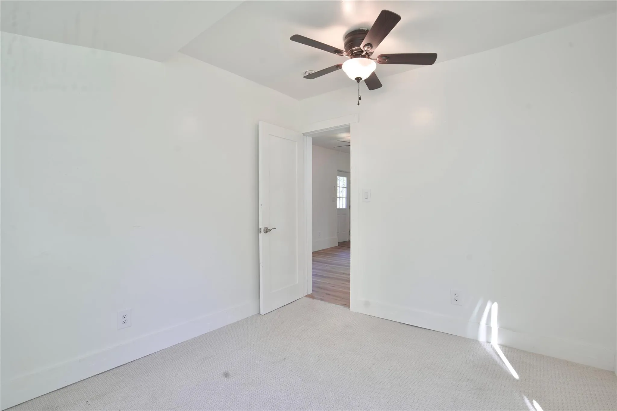 Unfurnished room featuring light carpet and a ceiling fan Unfurnished room featuring light carpet and a ceiling fan