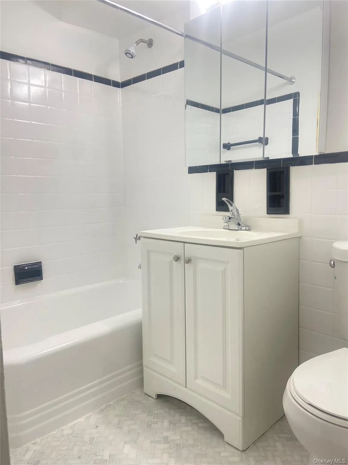 Bathroom featuring shower /combination, vanity, tile walls, and light tile patterned floors Bathroom featuring shower /combination, vanity, tile walls, and light tile patterned floors