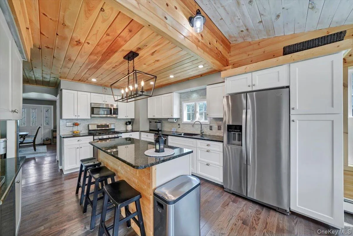 Kitchen with stainless steel appliances, dark wood finished floors, recessed lighting, decorative backsplash, and white cabinets Kitchen with stainless steel appliances, dark wood finished floors, recessed lighting, decorative backsplash, and white cabinets