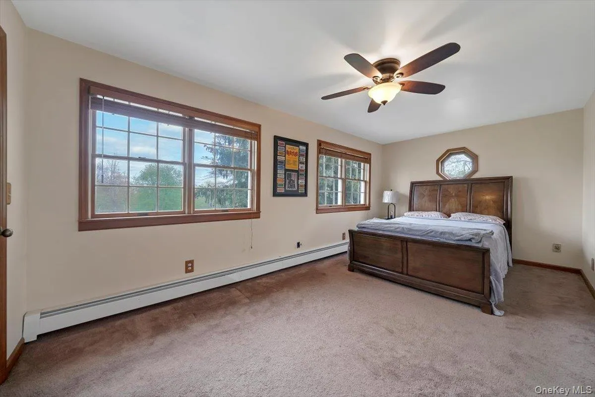 Bedroom with a baseboard radiator, carpet floors, and ceiling fan Bedroom with a baseboard radiator, carpet floors, and ceiling fan