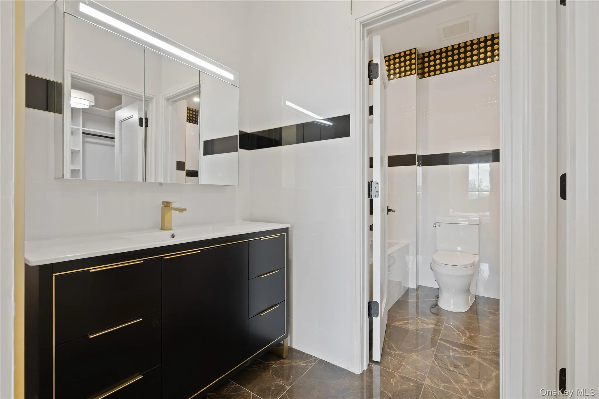 Bathroom with vanity, marble finish floors, and tile walls Bathroom with vanity, marble finish floors, and tile walls