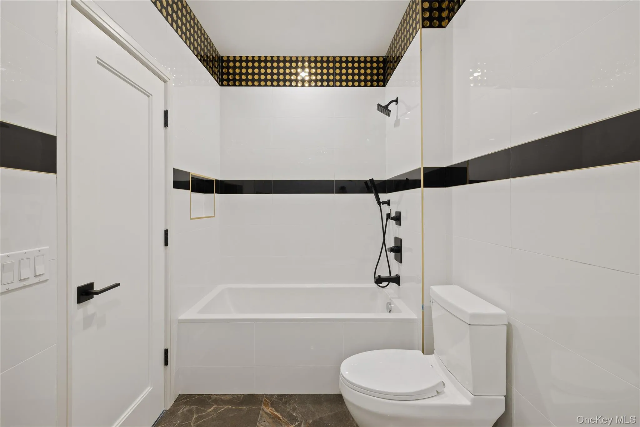 Full bath featuring tiled shower / bath combo, tile walls, and marble finish floors Full bath featuring tiled shower / bath combo, tile walls, and marble finish floors