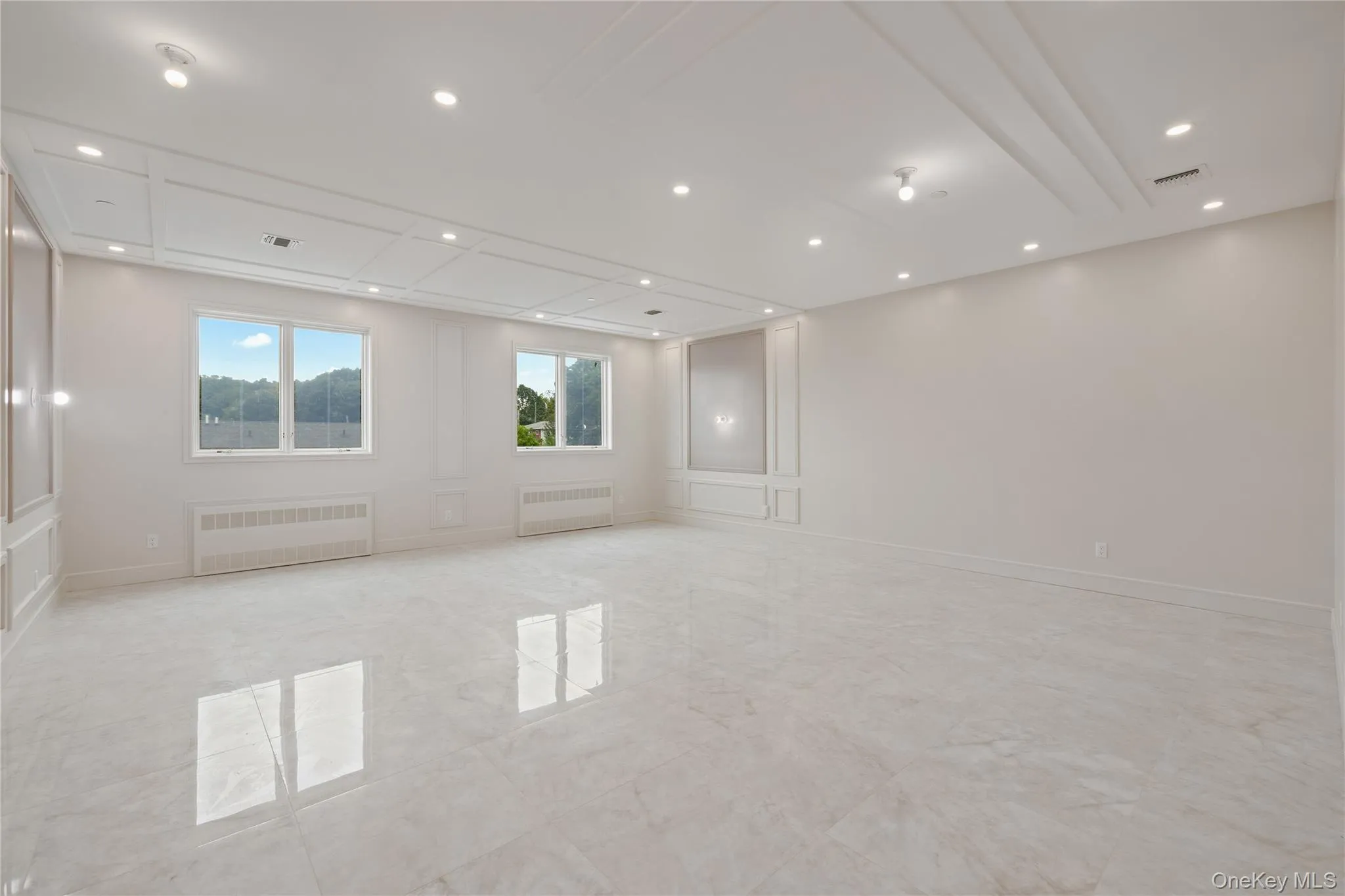 Empty room featuring radiator, light marble finish floors, and recessed lighting Empty room featuring radiator, light marble finish floors, and recessed lighting