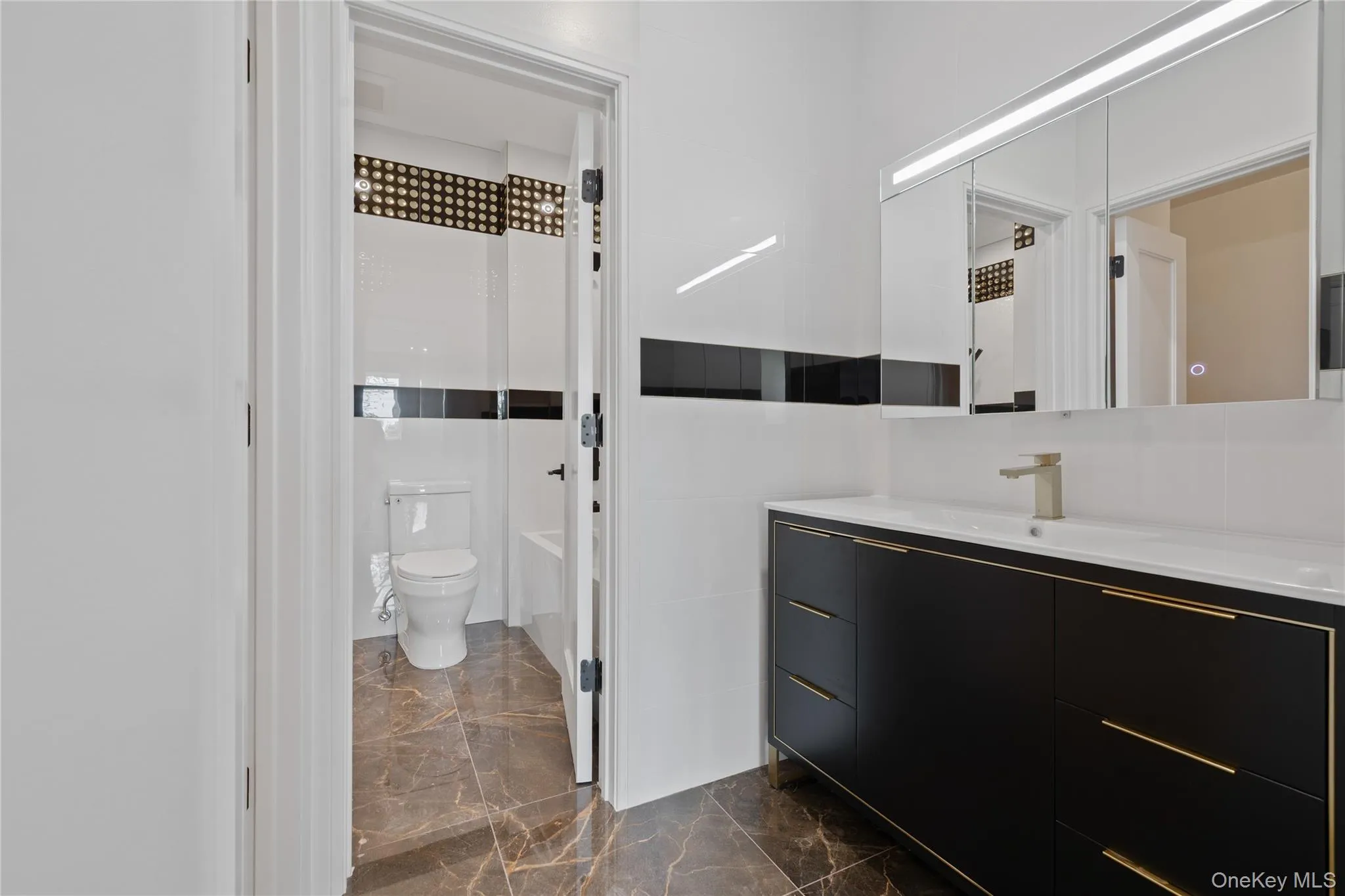 Bathroom with vanity, marble finish floors, and washtub / shower combination Bathroom with vanity, marble finish floors, and washtub / shower combination