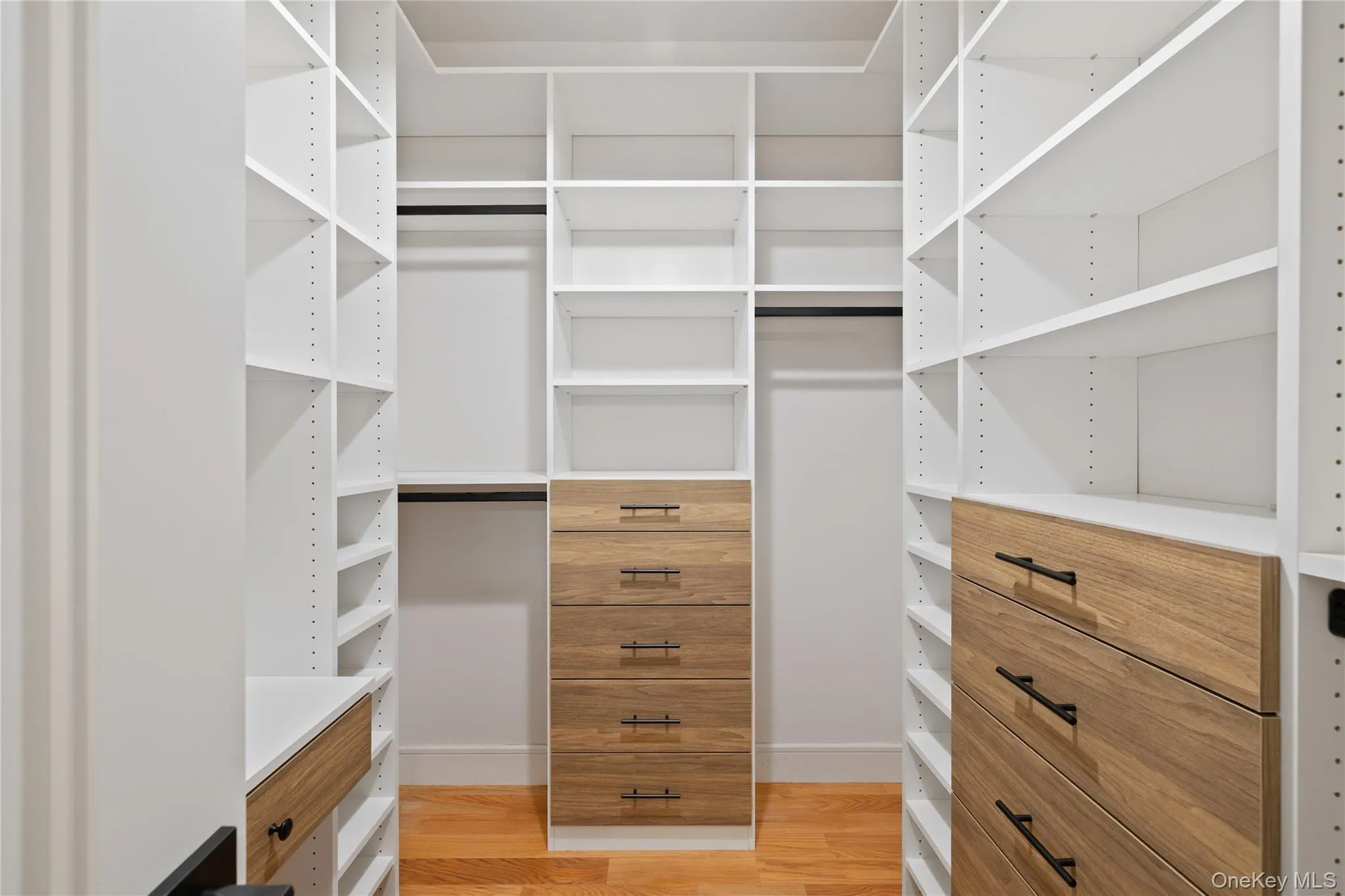 Walk in closet with light wood-style flooring Walk in closet with light wood-style flooring