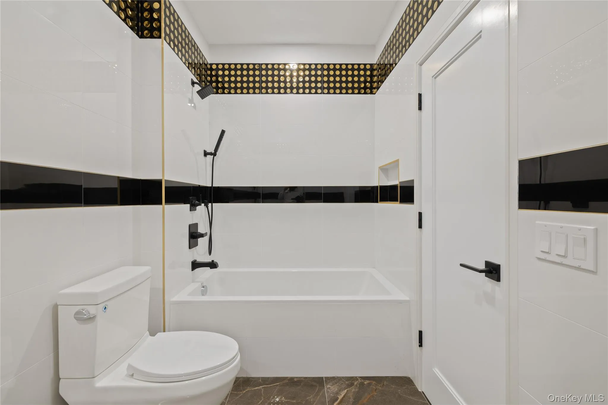 Bathroom featuring shower combination, marble finish floors, and tile walls Bathroom featuring shower combination, marble finish floors, and tile walls