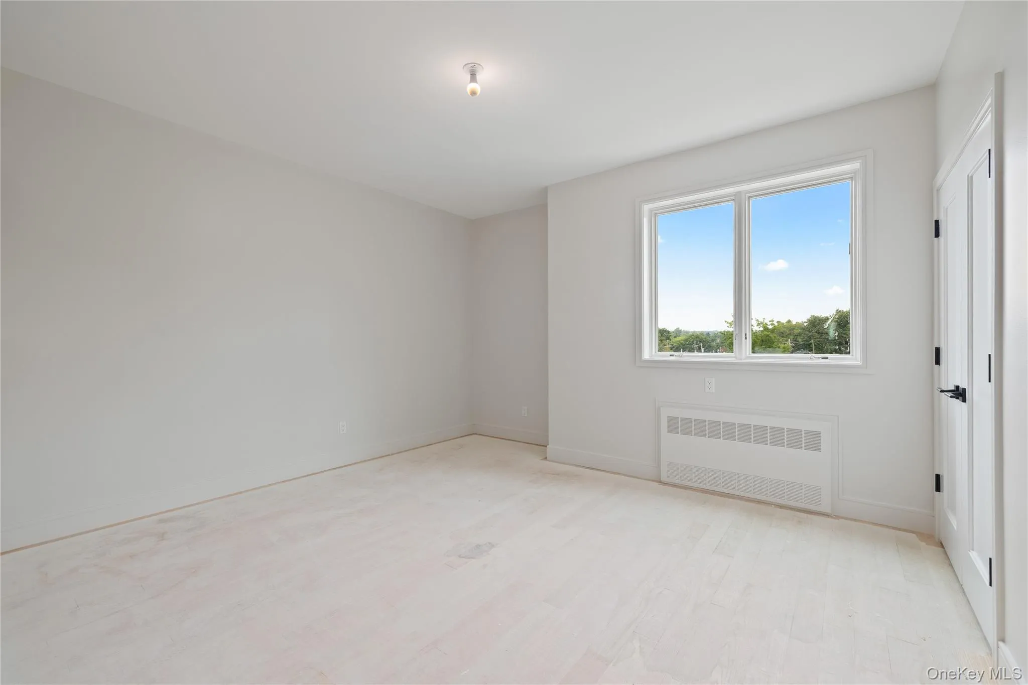 Empty room with radiator and light wood-style flooring Empty room with radiator and light wood-style flooring