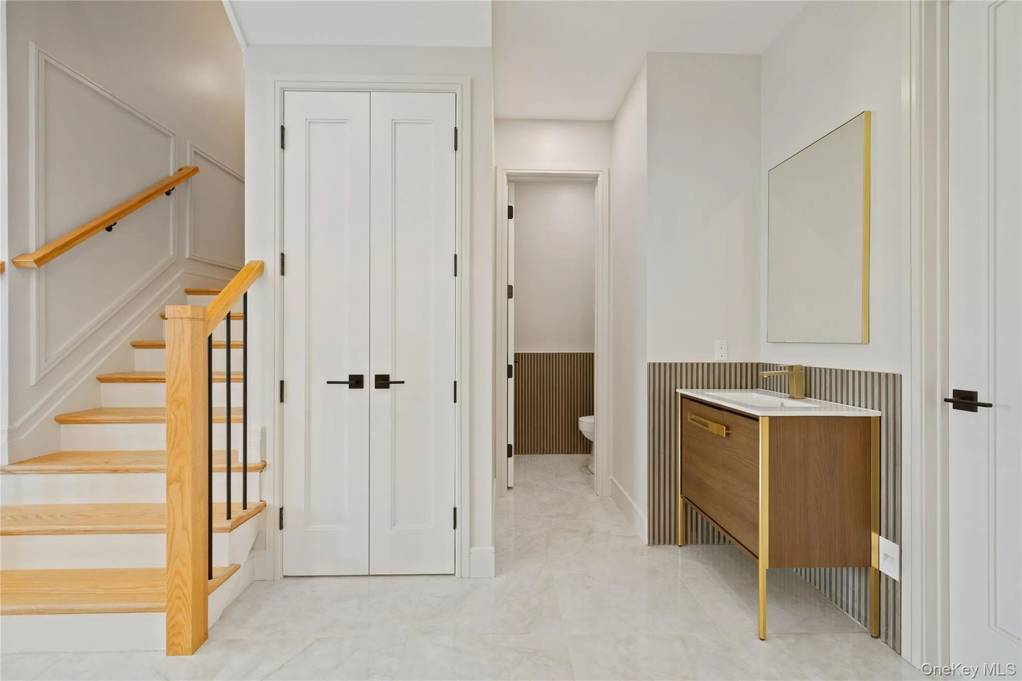 Full bathroom with wainscoting, vanity, marble finish floors, and a decorative wall Full bathroom with wainscoting, vanity, marble finish floors, and a decorative wall