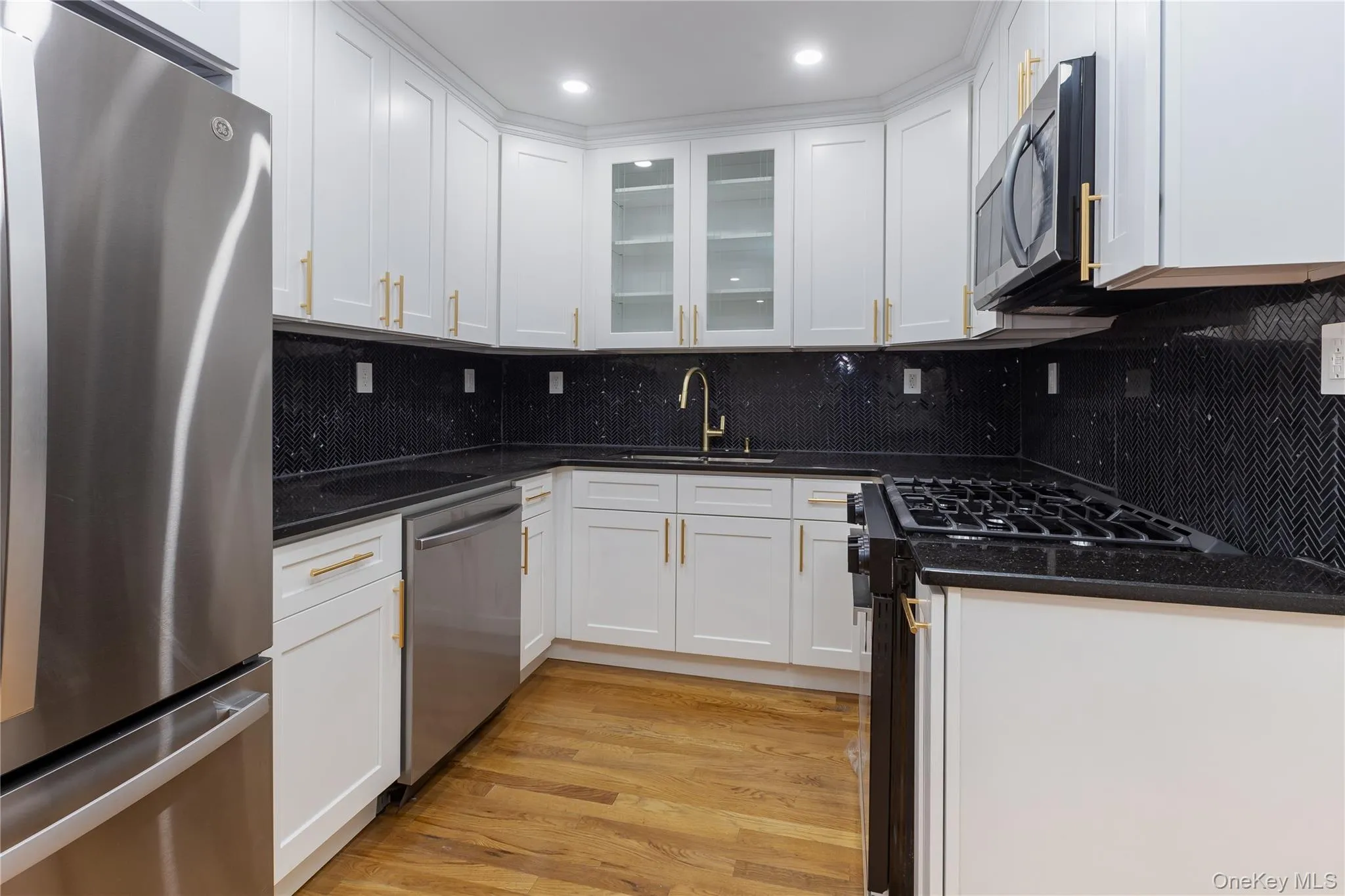 Kitchen featuring appliances with stainless steel finishes, decorative backsplash, white cabinetry, and recessed lighting Kitchen featuring appliances with stainless steel finishes, decorative backsplash, white cabinetry, and recessed lighting