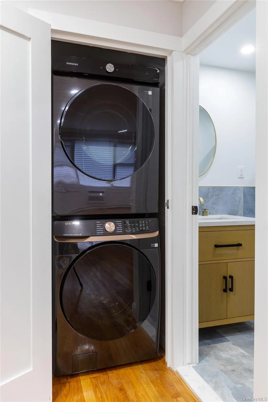 Washroom featuring stacked washer / drying machine and light wood-style flooring Washroom featuring stacked washer / drying machine and light wood-style flooring