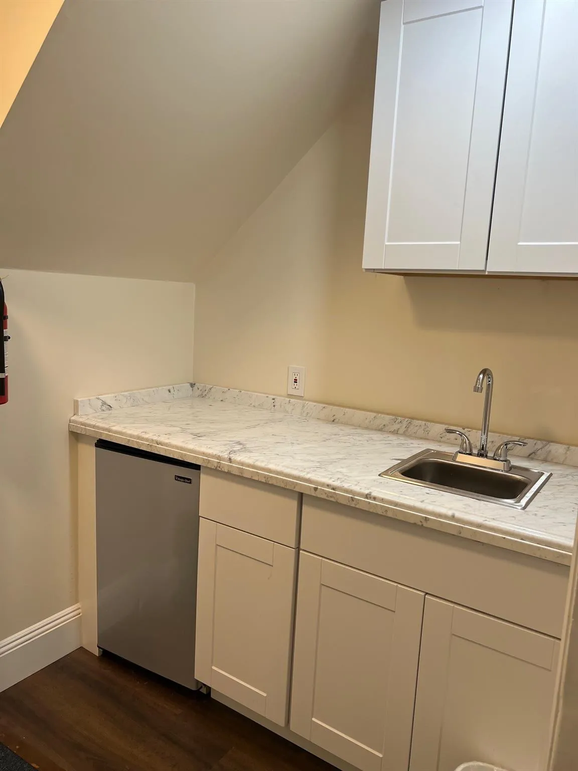 Kitchen featuring lofted ceiling, white cabinetry, dark wood-type flooring, light countertops, and dishwasher Kitchen featuring lofted ceiling, white cabinetry, dark wood-type flooring, light countertops, and dishwasher