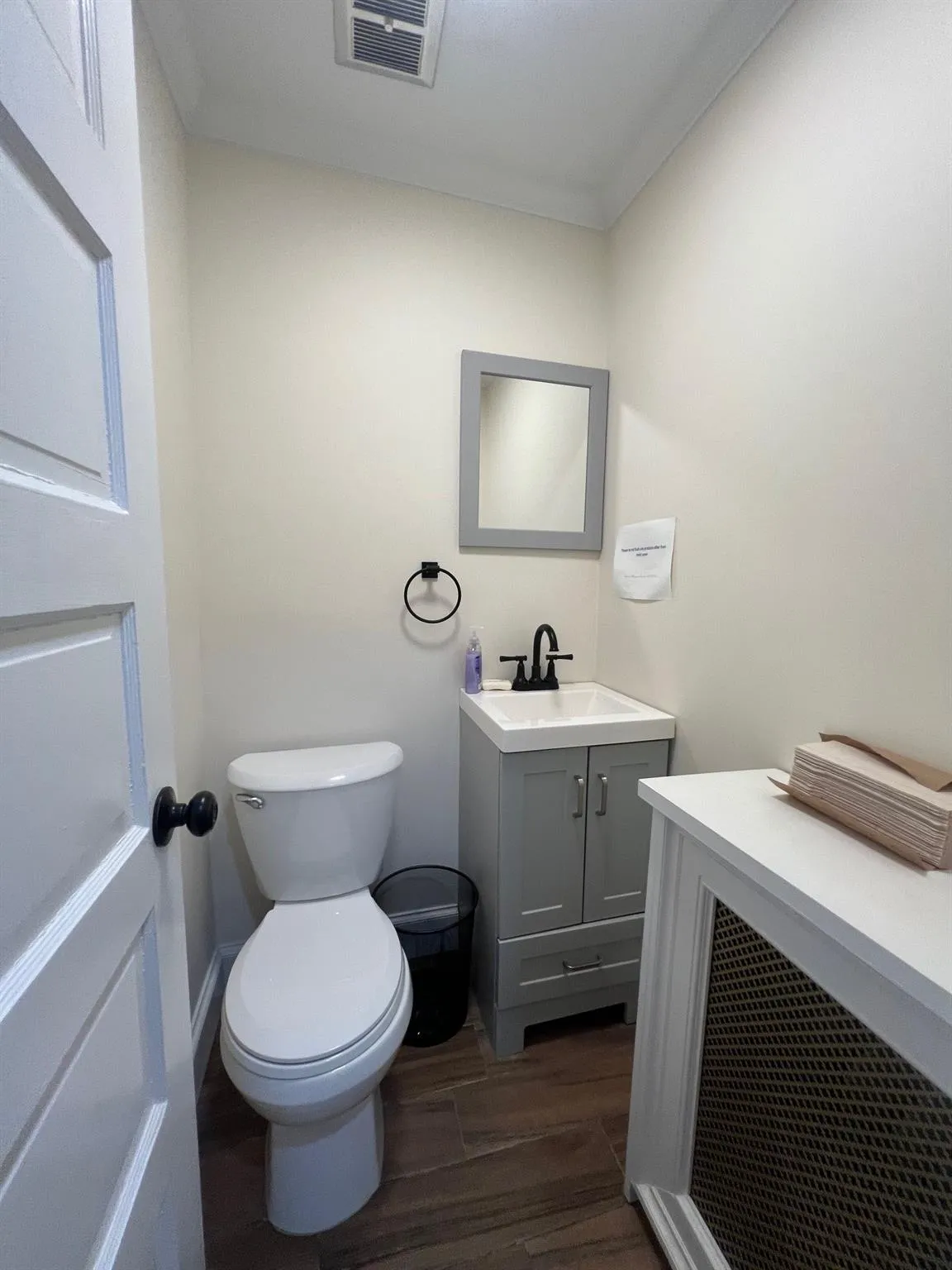 Half bath featuring vanity, wood finished floors, and ornamental molding Half bath featuring vanity, wood finished floors, and ornamental molding