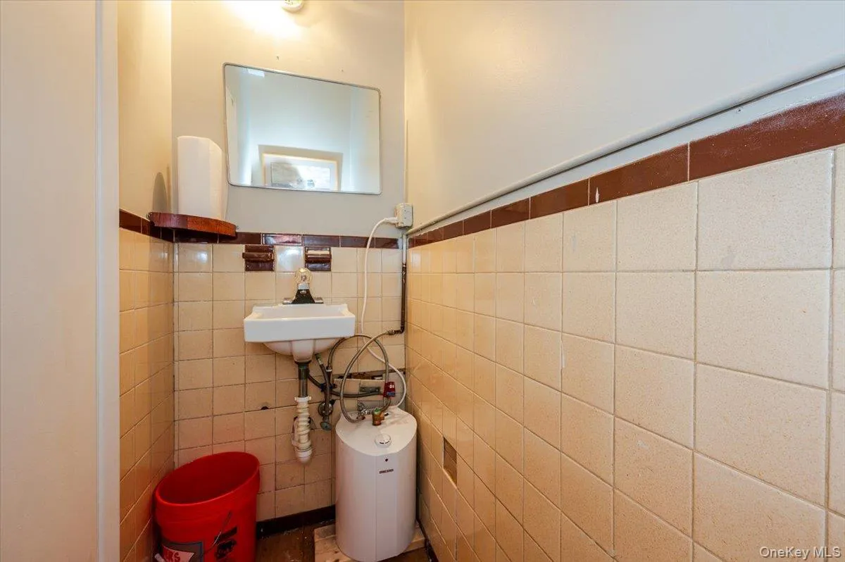 Half bathroom featuring wainscoting and tile walls Half bathroom featuring wainscoting and tile walls
