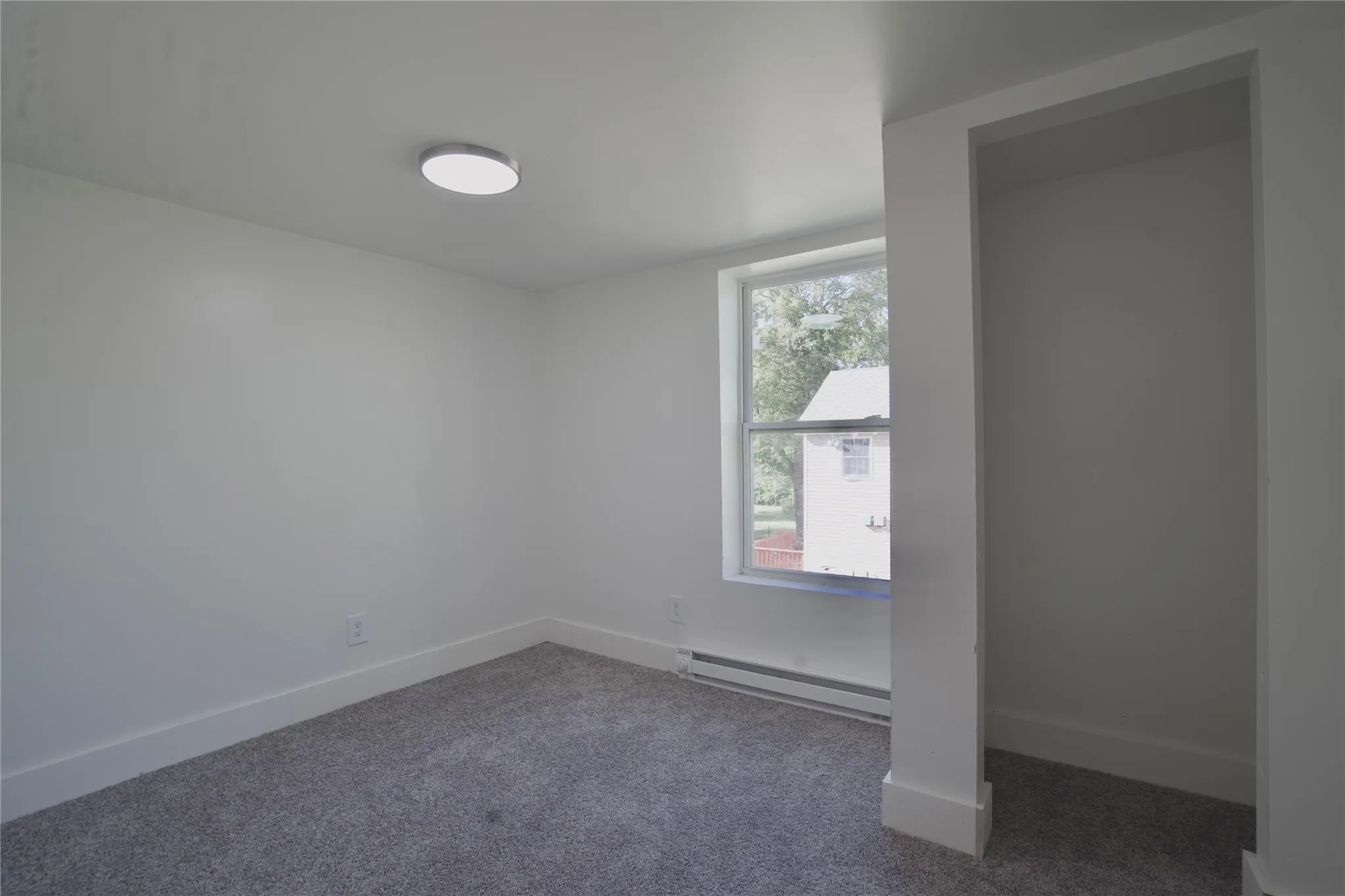Empty room with carpet and a baseboard heating unit Empty room with carpet and a baseboard heating unit