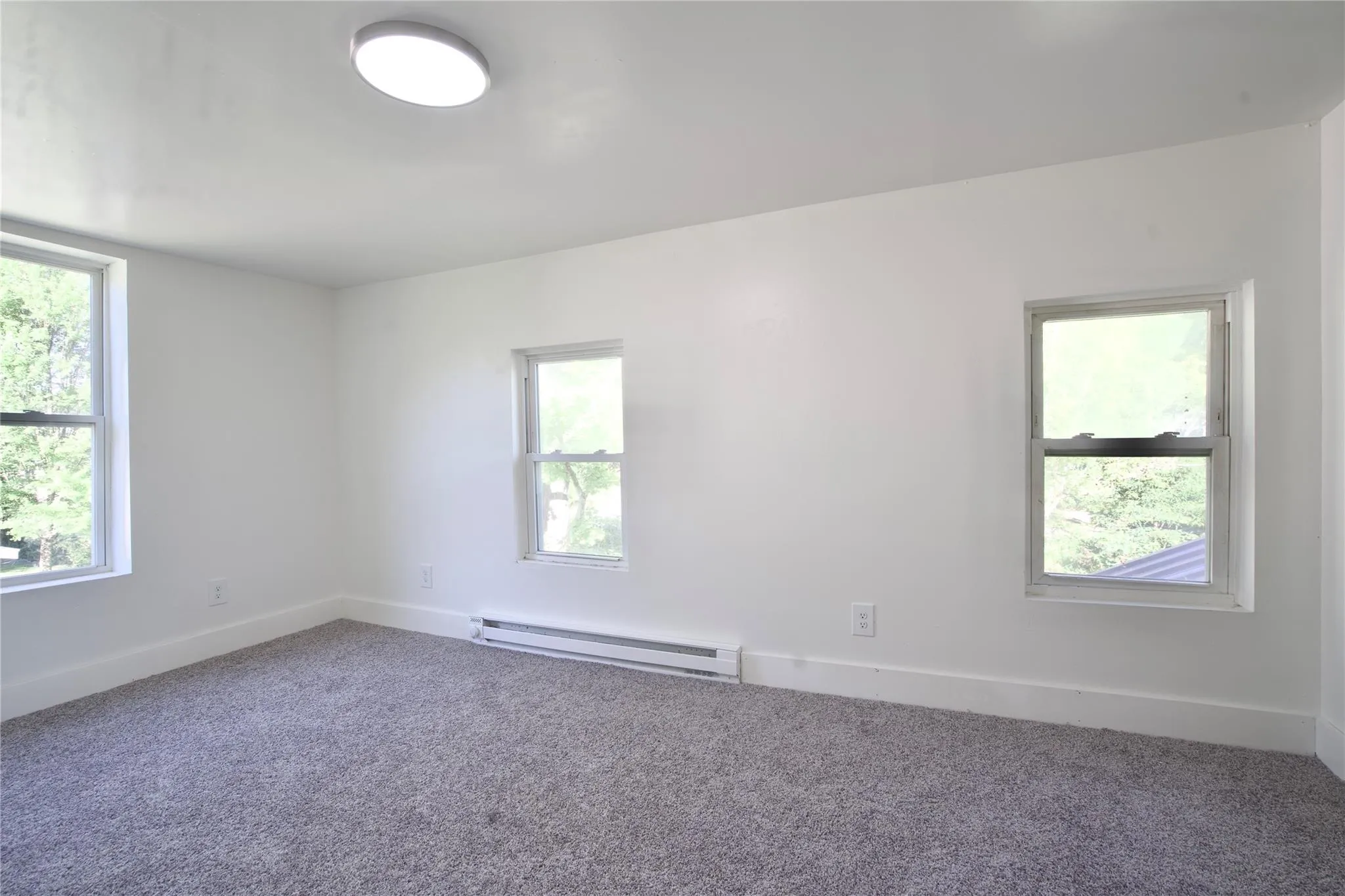 Carpeted empty room featuring baseboards and baseboard heating Carpeted empty room featuring baseboards and baseboard heating
