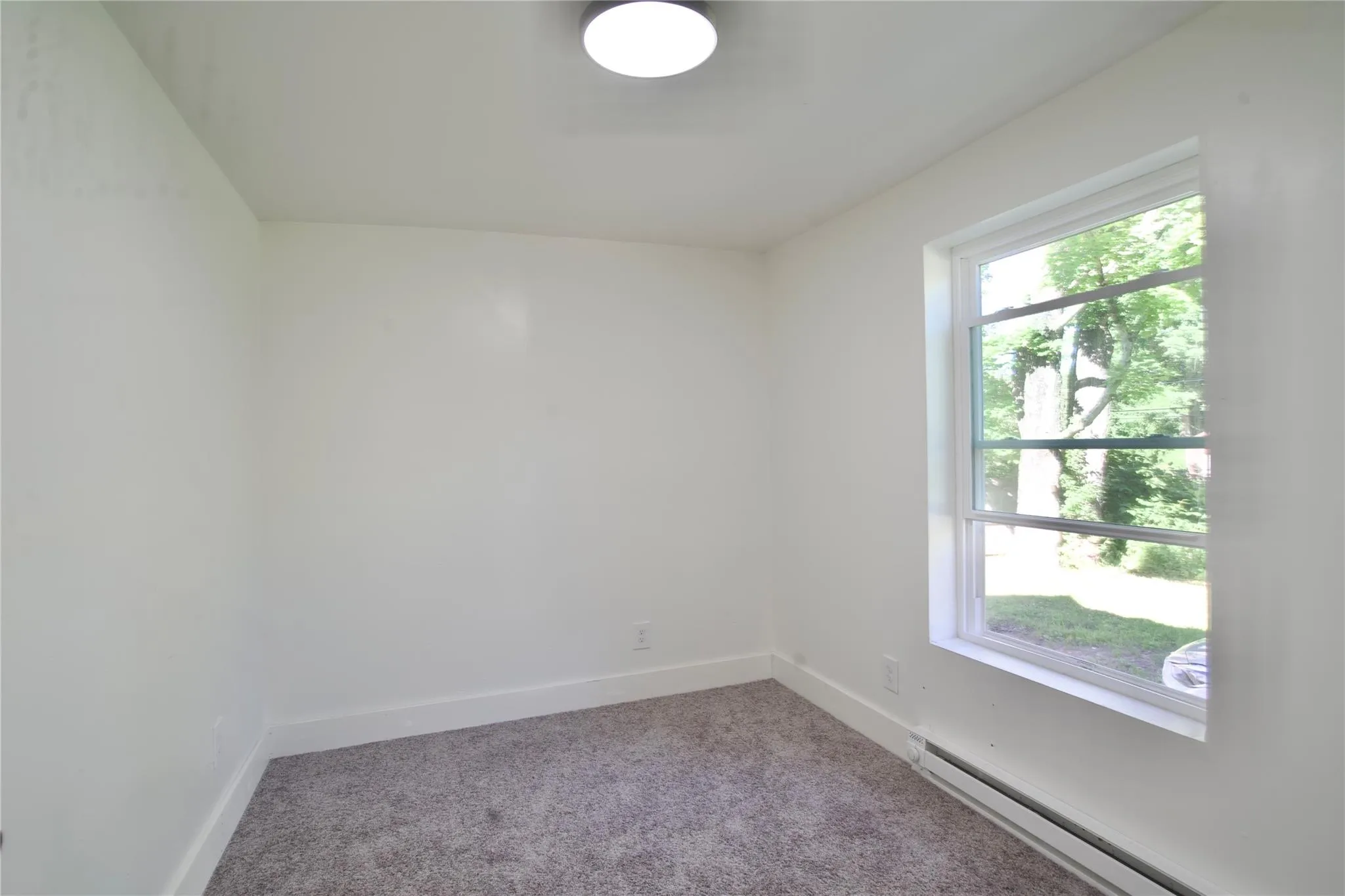 Unfurnished room with carpet flooring and baseboard heating Unfurnished room with carpet flooring and baseboard heating