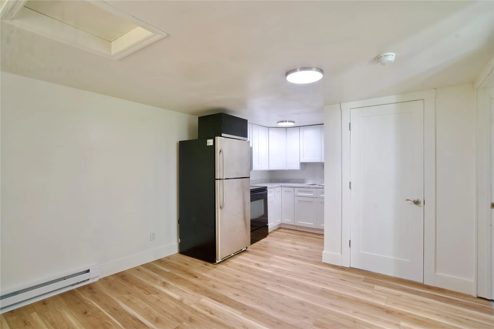 Kitchen with freestanding refrigerator, a baseboard heating unit, light wood-type flooring, and black electric range Kitchen with freestanding refrigerator, a baseboard heating unit, light wood-type flooring, and black electric range