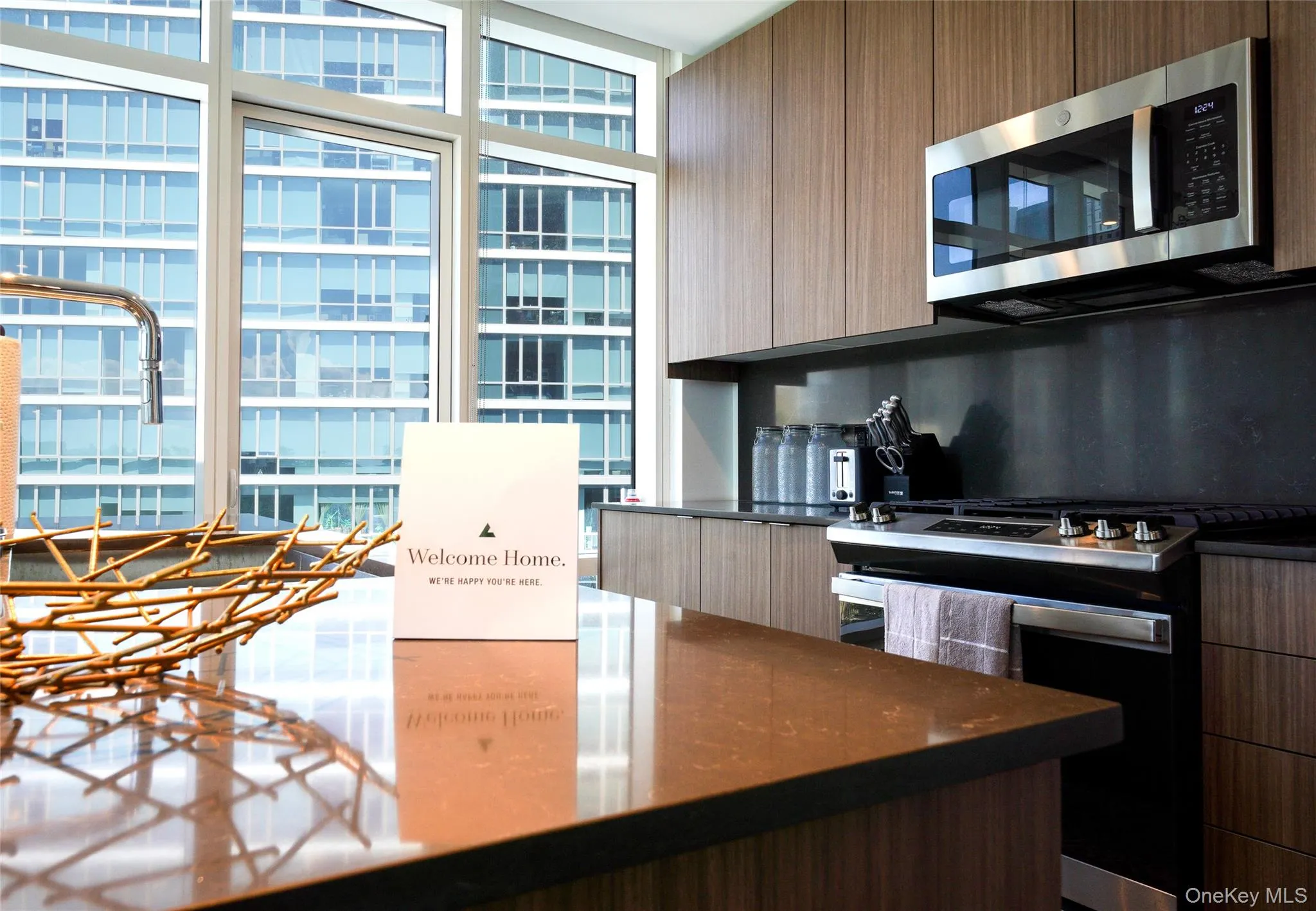 Kitchen featuring modern cabinets, slide in range oven, stainless steel microwave, expansive windows, and dark stone countertops Kitchen featuring modern cabinets, slide in range oven, stainless steel microwave, expansive windows, and dark stone countertops