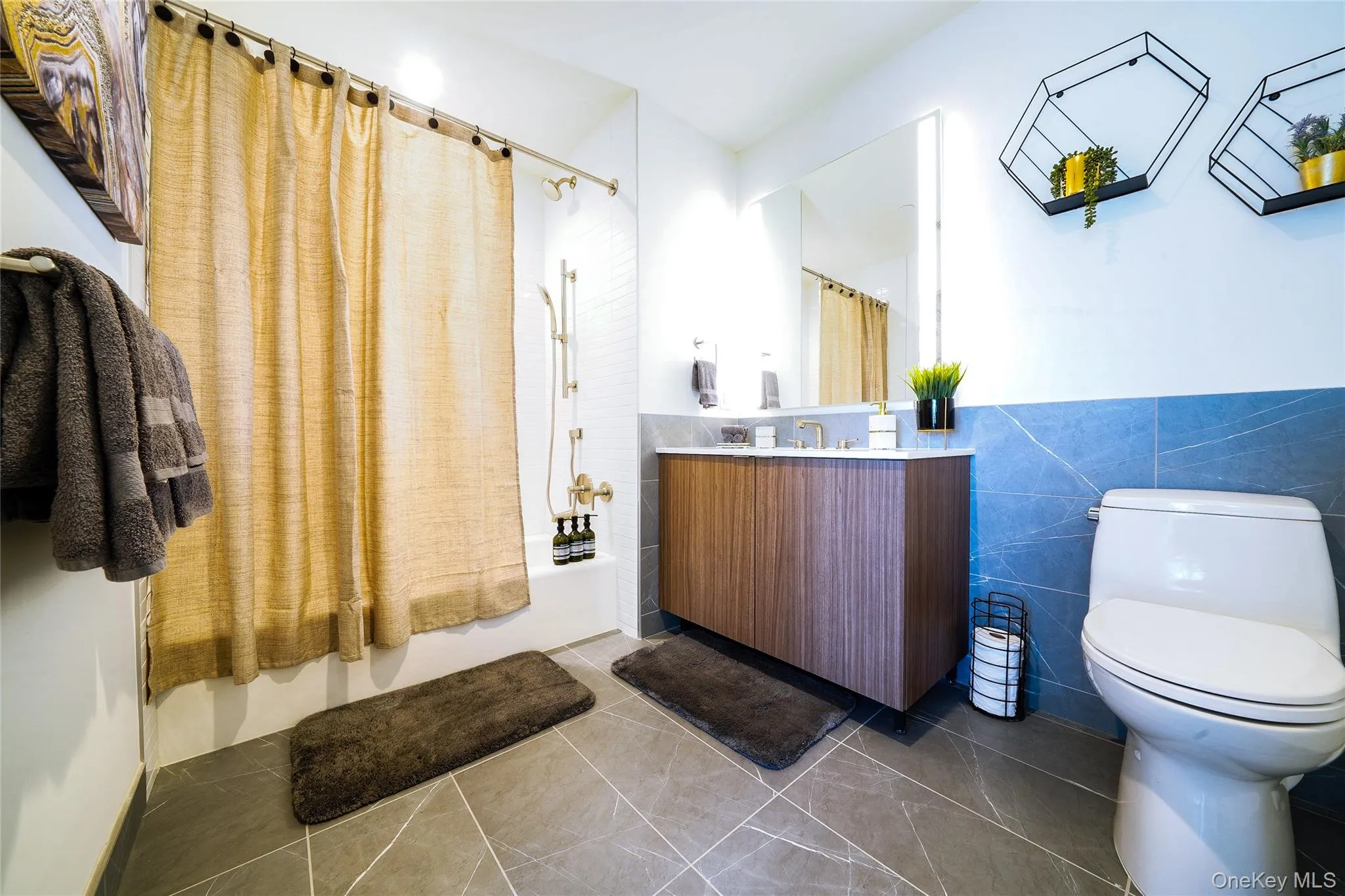 Bathroom with shower / tub combo, tile patterned floors, tile walls, and vanity Bathroom with shower / tub combo, tile patterned floors, tile walls, and vanity