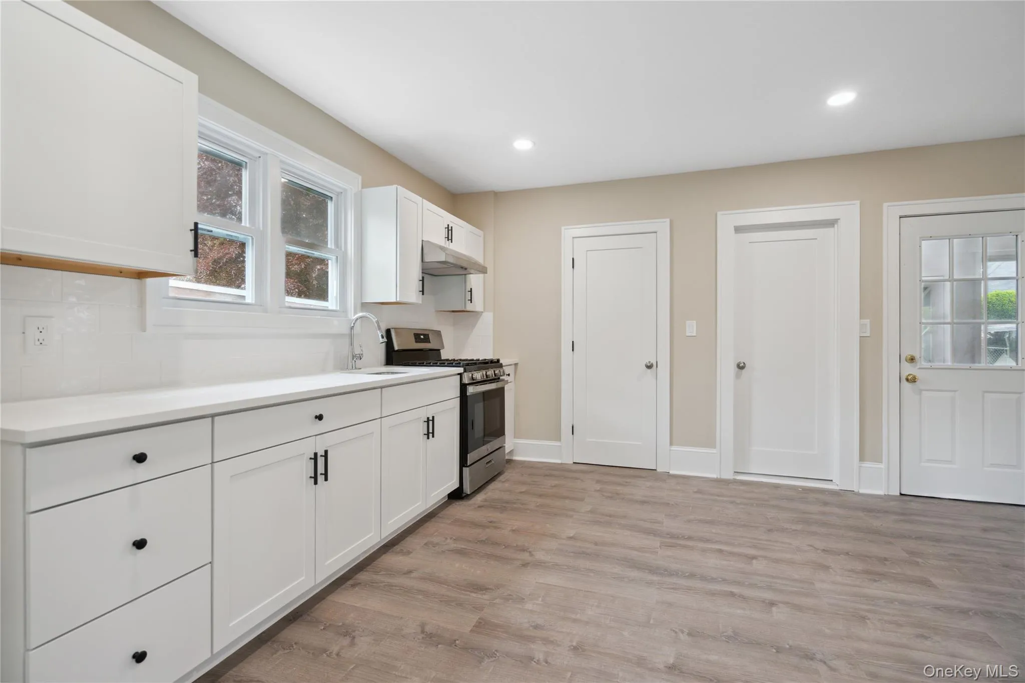 Kitchen with stainless steel gas range oven, light wood finished floors, white cabinetry, light countertops, and recessed lighting Kitchen with stainless steel gas range oven, light wood finished floors, white cabinetry, light countertops, and recessed lighting