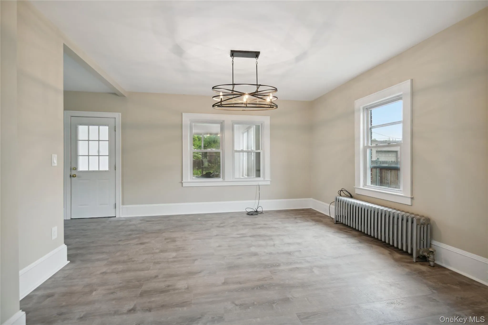 Unfurnished dining area featuring radiator heating unit, plenty of natural light, wood finished floors, and a chandelier Unfurnished dining area featuring radiator heating unit, plenty of natural light, wood finished floors, and a chandelier