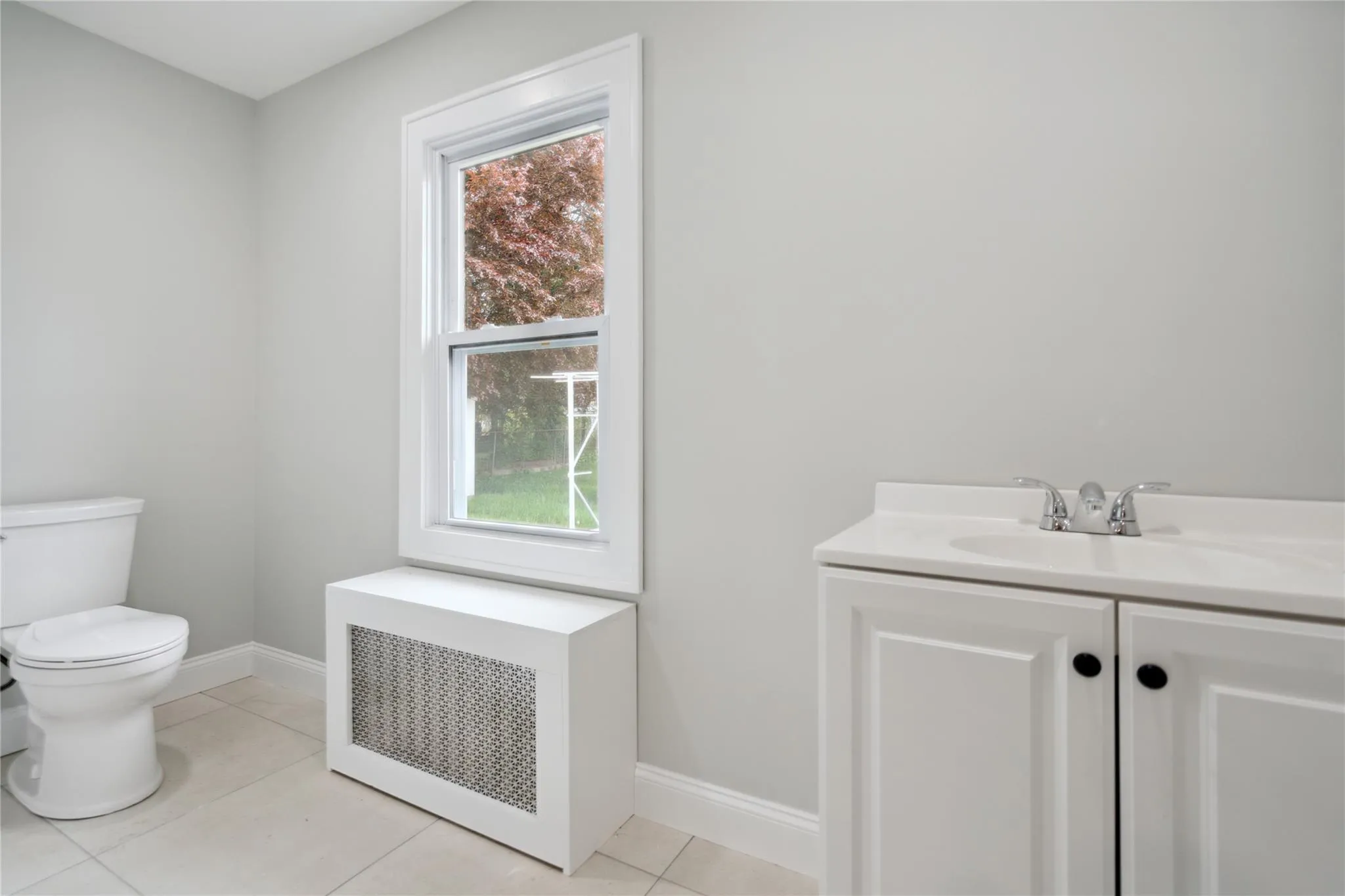 Bathroom with radiator heating unit, vanity, and tile patterned flooring Bathroom with radiator heating unit, vanity, and tile patterned flooring