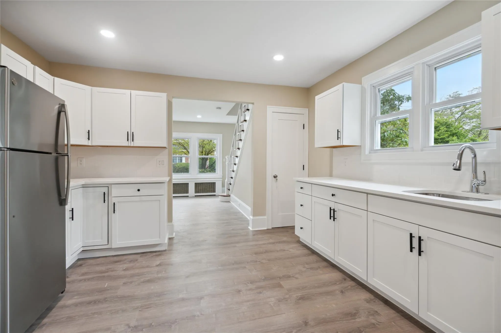 Kitchen featuring freestanding refrigerator, light wood finished floors, white cabinets, light countertops, and recessed lighting Kitchen featuring freestanding refrigerator, light wood finished floors, white cabinets, light countertops, and recessed lighting