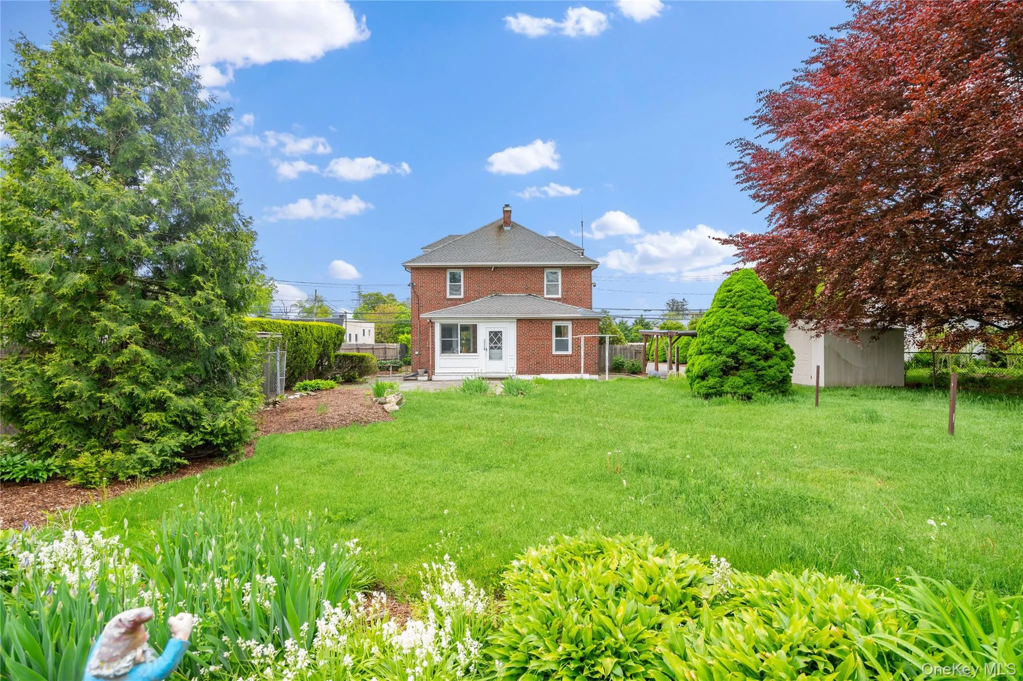 Rear view of house with brick siding, a fenced backyard, a storage unit, and a chimney Rear view of house with brick siding, a fenced backyard, a storage unit, and a chimney