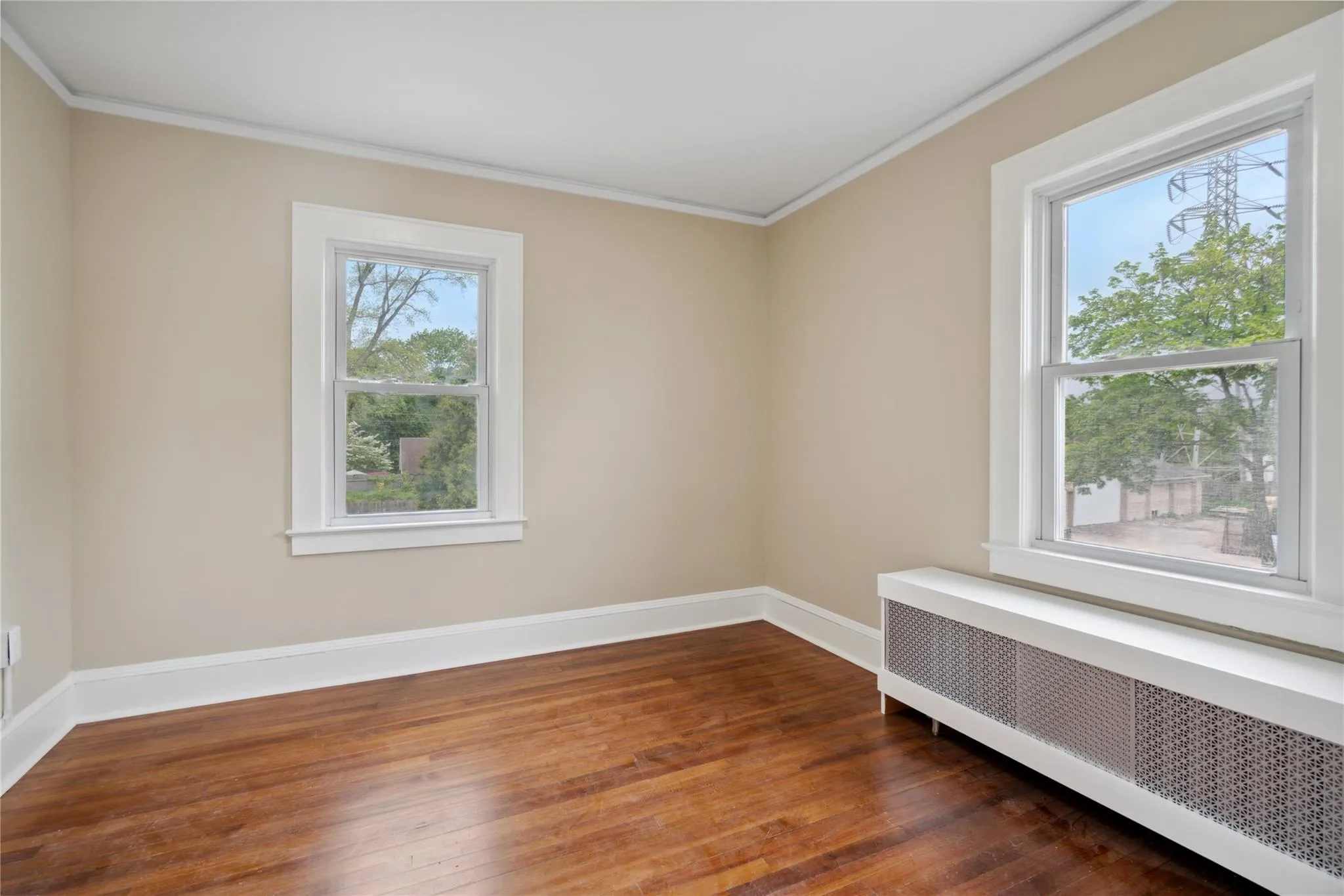 Spare room featuring radiator heating unit, hardwood / wood-style flooring, and ornamental molding Spare room featuring radiator heating unit, hardwood / wood-style flooring, and ornamental molding
