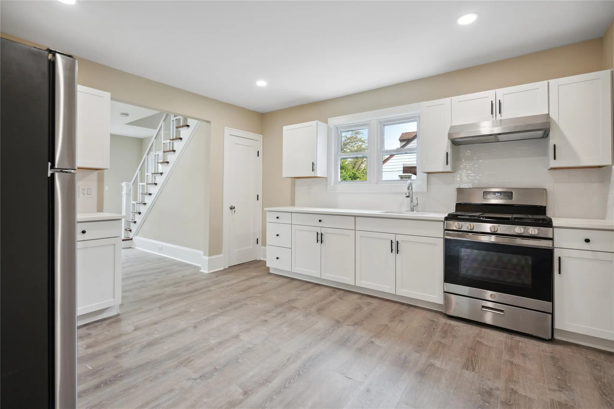 Kitchen featuring appliances with stainless steel finishes, under cabinet range hood, light countertops, white cabinets, and recessed lighting Kitchen featuring appliances with stainless steel finishes, under cabinet range hood, light countertops, white cabinets, and recessed lighting