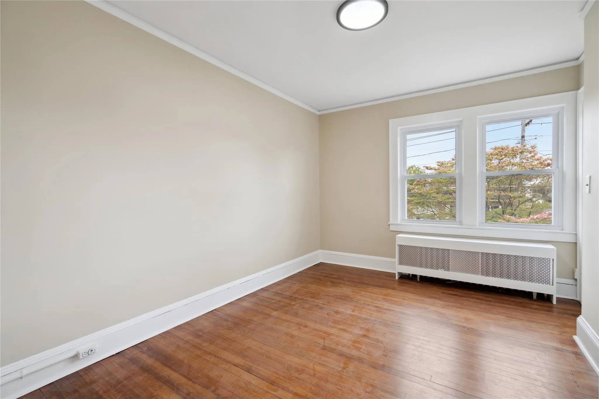 Unfurnished room with radiator heating unit, hardwood / wood-style floors, and ornamental molding Unfurnished room with radiator heating unit, hardwood / wood-style floors, and ornamental molding