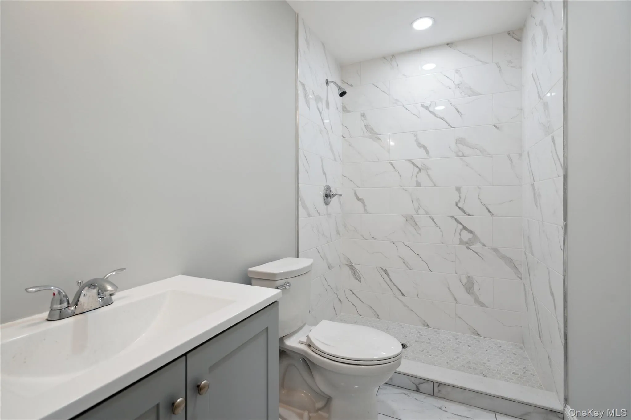 Full bath featuring tiled shower, vanity, and marble look tile flooring Full bath featuring tiled shower, vanity, and marble look tile flooring